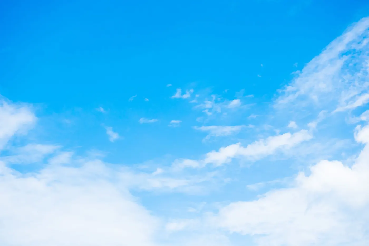 Clear blue sky with soft white clouds